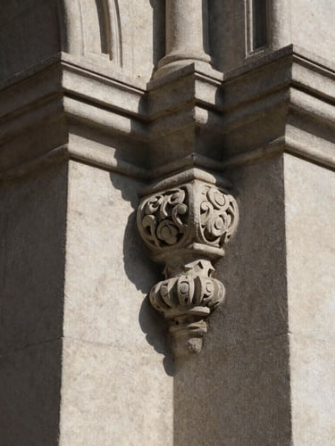 Close-up of carved stone architectural details on a historic trust building, long dramatic shadows, soft natural light.