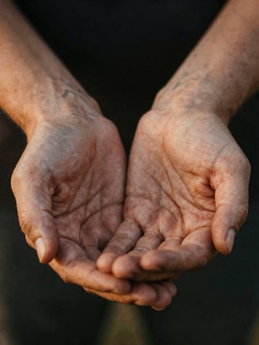Close-up of hands clasped in support, weathered hands, warm natural low-key lighting, authentic depth of field.