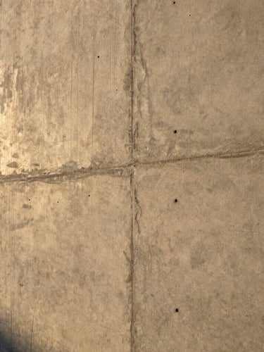 Close-up of a pristine, freshly poured architectural concrete wall, sharp focus, dramatic side lighting showing texture