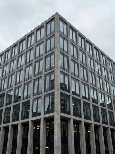 Wide-angle architectural shot of a modern concrete and glass office building in London under overcast daylight, sharp focus, desaturated slate and navy tones, 35mm.