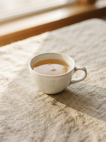 Minimalist close-up of a delicate white porcelain teacup on raw linen, soft morning daylight casting long shadows, warm ivory tones, editorial 35mm photography