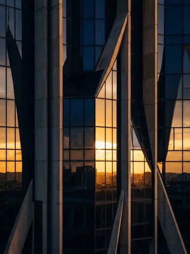 Extreme close-up of a modernist glass facade in Brasília reflecting golden hour light, sharp geometric angles, architectural shadows, deep navy and warm gold tones.