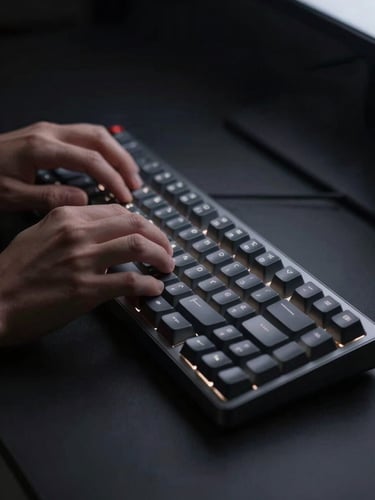 Minimalist dark-mode digital photography of hands typing on a sleek mechanical keyboard, soft localized glowing light from a screen, deep charcoal and silver tones, shallow depth of field