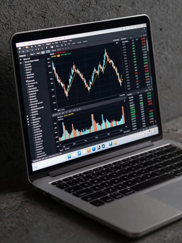 Close-up of a high-end dark metallic laptop screen displaying clean financial charts and code, dramatic side lighting, dark concrete background