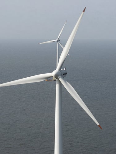 Top-down orthographic view of an industrial wind turbine array, clean white blades against a desaturated grey sea, overcast daylight, architectural grid lines overlaid.