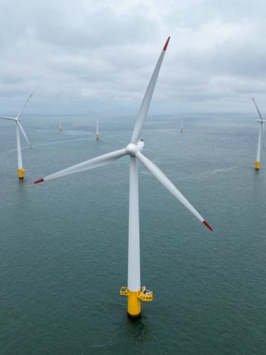 Top-down orthographic drone view of a modern offshore wind turbine array in overcast daylight, crisp technical composition, desaturated teal water.