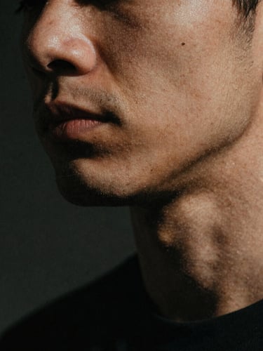 Portrait close-up of a man's jawline, subtly clenched, strong shadows, moody natural light, raw film grain, 35mm lens.