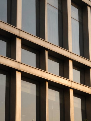 Tight architectural detail of a premium office facade in Global Foyer, Gurugram, warm champagne gold accents on dark metal frames, soft afternoon sun, 35mm lens