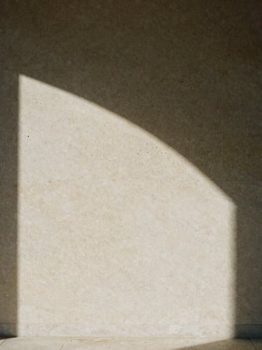 Low-angle sunlight hitting a raw Lioz limestone wall, deep shadows, textured 35mm film grain, minimalist Portuguese interior