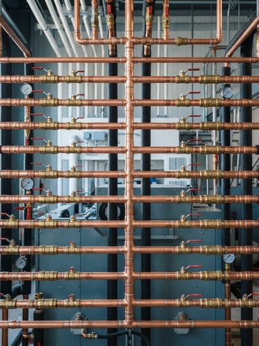 Symmetrical close-up of immaculate copper piping arrays in a modern mechanical room, bright natural utility lighting, sharp focus, 35mm