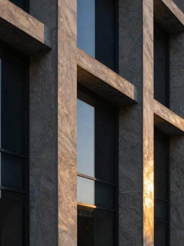 Refined architectural detail of a modern concrete and glass facade at twilight, golden light reflecting on polished marble columns, sharp focus, 35mm.