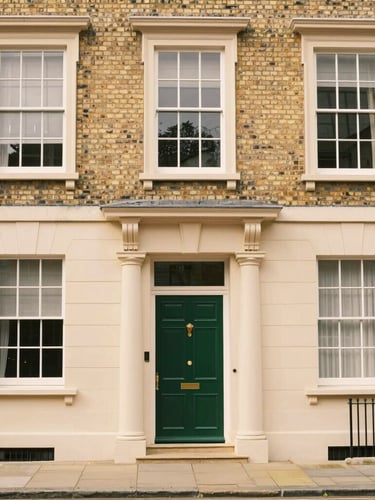 Wide shot of the historic Revinon Ltd townhouse facade in Hertford, UK, under soft overcast daylight, elegant Georgian architecture, forest green door, warm cream brick, professional and inviting, 35mm