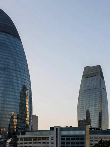 Wide environmental shot of Baku business district skyline in the morning, high contrast modern glass towers, cool daylight, professional architectural perspective.