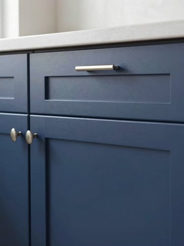 Close-up of a beautifully refinished modern kitchen cabinet door, flawless matte navy finish, clean silver hardware, bright natural light