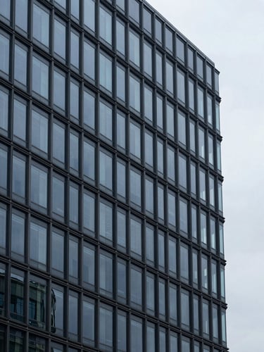 Minimalist corporate photography of a modern glass and steel office tower reflecting cool overcast daylight, deep navy and steel gray tones, architectural framing, 35mm