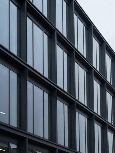 Architectural crop of a modern corporate office facade, steel and glass geometry, cool overcast daylight, 35mm