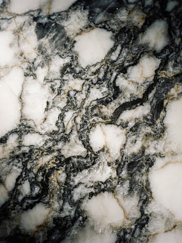 Extreme macro close-up of premium Calacatta marble veins, dramatic low-key side-lighting, deep charcoal and gold undertones, sharp focus