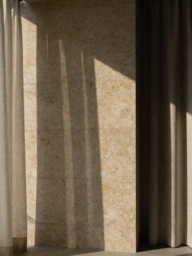 Architectural photography of a brutalist luxury concrete wall meeting warm travertine stone and soft linen curtains, dramatic natural side light, deep shadows, Hasselblad medium format.