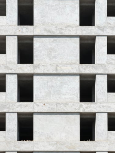 Straight-on architectural shot of modern building under construction with neatly stacked lightweight concrete panels, bright natural daylight, crisp details, 35mm lens