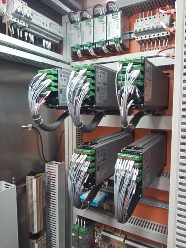 Industrial electrical control panel featuring organized PLC modules and wired servo drives for automation.