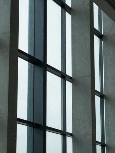 Abstract geometric patterns of concrete and glass architectural columns, sharp corporate daylight, cool tones, clean office window light, 35mm