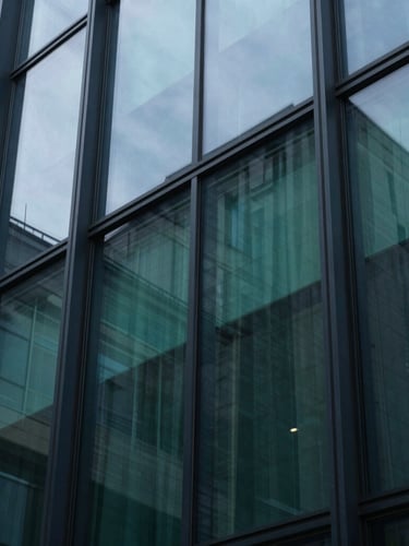 Extreme macro close-up of a structured architectural glass facade reflecting cool daylight, sharp shadows, deep navy and emerald tones, 35mm