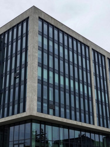 Wide architectural view of a modern concrete financial headquarters, sharp overcast daylight, clean lines, minimalist corporate exterior, 35mm