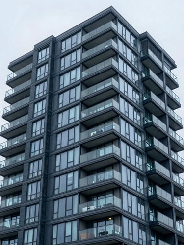 Sharp architectural photography of a modern Vancouver condominium facade, bright overcast daylight, cool blue tones, high clarity, 35mm