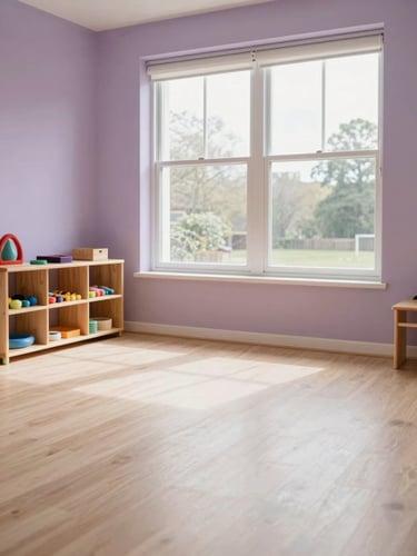 Soft natural light from a north-facing window falling across a calm children's therapy room interior, small wooden shelves with tactile materials in the left third, generous empty floor space, pale lilac and cream tones, no people
