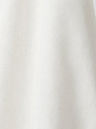 Macro close-up of a finely woven breathable cotton-silk fabric, showing subtle texture and natural drape, soft diffused natural daylight, clean white background, sharp focus, plenty of negative space to the left.