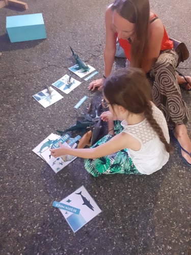 Petite fille qui joue avec des requins et sa maman