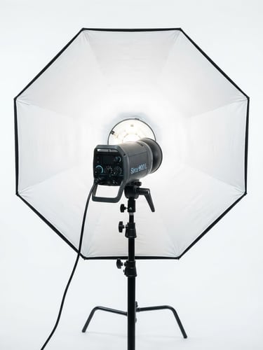 Professional studio flash strobe with softbox, sharp reflections on glass, clean white studio backdrop, bright high-key lighting, 85mm lens