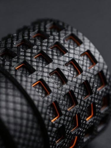 Extreme macro shot of a black 3D printed carbon-fiber lattice structure, dramatic side-lit studio lighting, orange rim light highlighting microscopic layer lines, sharp focus on textures, 100mm lens, dark charcoal background