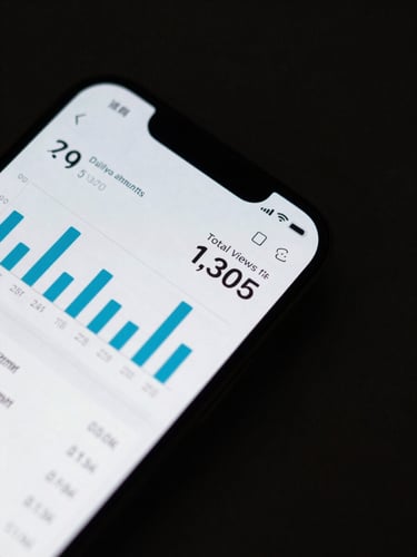 Close-up overhead flat-lay of a smartphone screen displaying a clean analytics dashboard — a vertical bar chart of daily view counts, a bold number showing total views, and a per-card breakdown list, screen lit with cool studio strobe, dark background, high contrast, no text visible