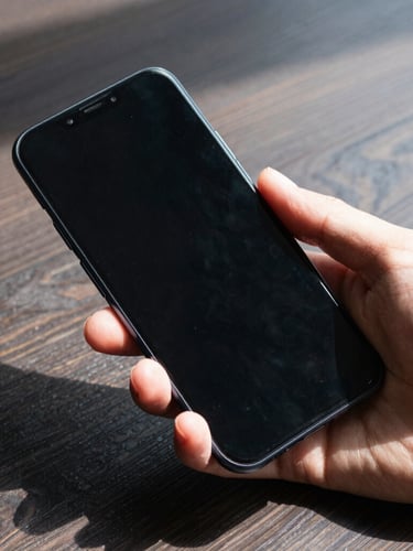 Macro shot of a hand holding a clean Android smartphone showing a minimalist black interface, sharp daylight casting strong geometric shadows on a dark wooden table