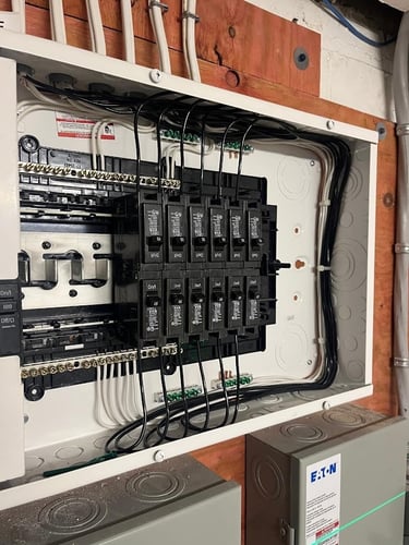 Residential electrical panel with circuit breakers installed and wires neatly routed for home power distribution.