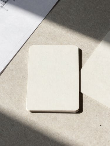 Overhead flat-lay of physical research materials, architectural blueprints, and structured cards on a minimalist table, natural north-facing daylight.