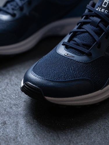 Close-up macro shot of athletic gear on a dark textured surface, cool tones, sharp shadows, dramatic lighting
