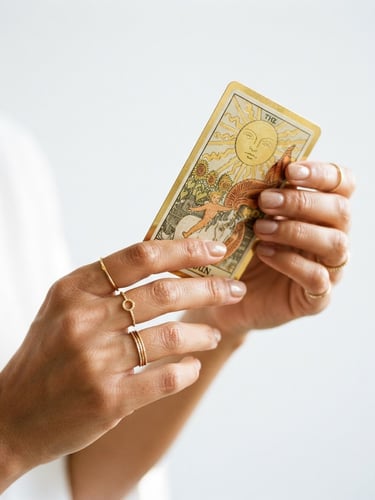 Close-up macro shot of hands with delicate gold rings holding a gold-rimmed tarot card, bright natural daylight, soft golden highlights, minimalist white background, 35mm