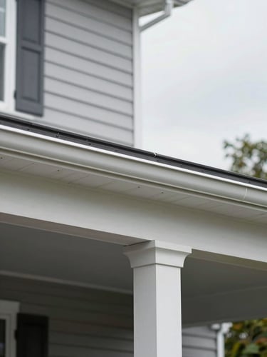 Close detail shot of a finished aluminum patio cover attached to a home exterior in Delaware, overcast daylight, clean fascia trim and post base visible, neutral gray siding in background, no people