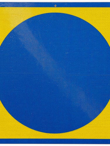 Macro shot of a reflective blue and yellow industrial safety sign, showing the honeycomb texture of the reflective vinyl, high contrast daylight, sharp focus