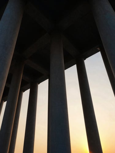 Dramatic low-angle view of massive structural steel columns rising into a golden hour sky, architectural precision, cinematic lighting