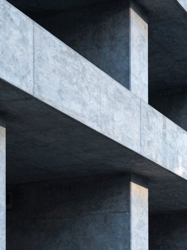 A vertical portrait of clean industrial workspace architectural details, sharp concrete lines, cool daylight casting deep shadows.