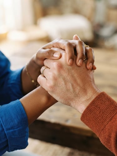 Close-up of two diverse hands clasped firmly in solidarity, warm natural daylight, soft focus, 35mm editorial photography, royal blue and orange accents.