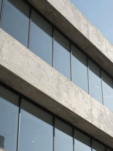 Macro detail of high-quality architectural concrete and glass facade under bright midday sun, clean lines