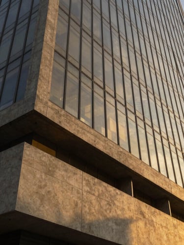 Ultra-wide architectural shot of a modern corporate building in São Paulo, sharp concrete angles and glass facade reflecting a warm yellow sunset light, high-contrast shadows