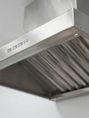 Close-up of a sparkling clean stainless steel commercial exhaust hood, bright crisp utility lighting, sharp focus on clean metal surfaces.