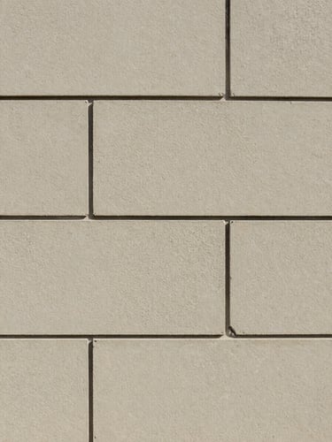 Straight-on shot of clean, perfectly uniform mortar lines on a newly constructed retaining wall in bright daylight.