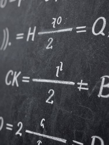 Macro shot of elegant mathematical equations handwritten in white chalk on a clean dark slate chalkboard, shallow depth of field, sharp focus on central tensor notation.