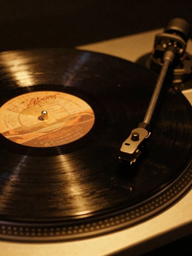 Low-key editorial close-up of a vintage vinyl record spinning on a high-end turntable, warm golden spotlighting, deep shadows, rich black and amber tones, 35mm film grain